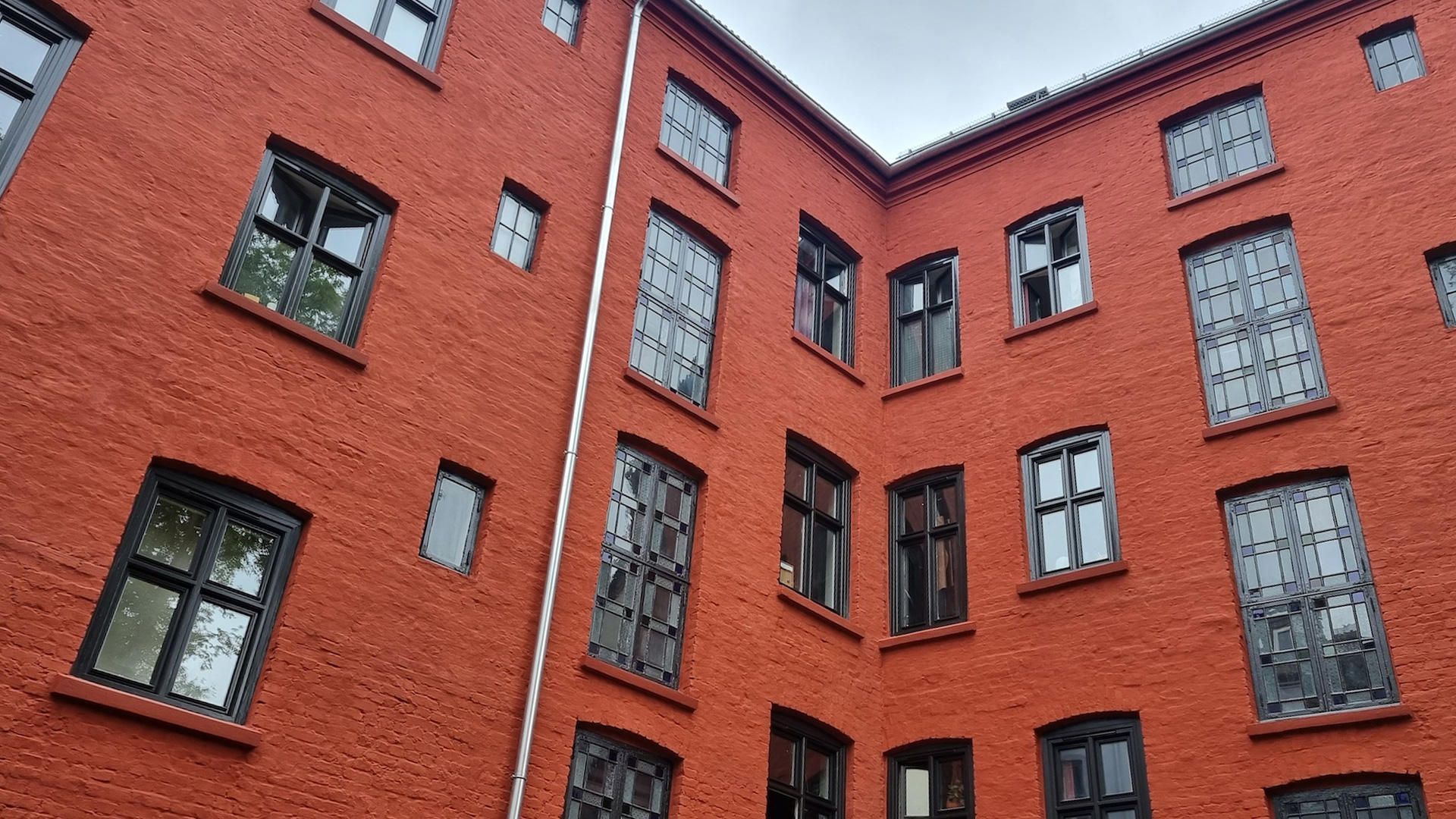 Bilde av rødmalt murfasade med svarte vinduer